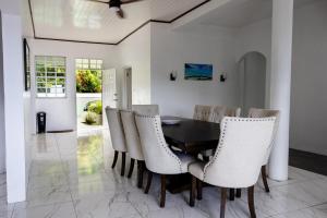 a dining room with a black table and white chairs at Sea and Summit Villa in Roseau