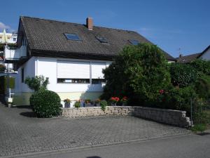 uma casa branca com um muro de retenção à frente. em Ferienwohnung am Bodensee em Uhldingen-Mühlhofen