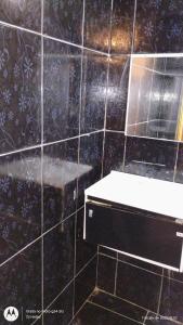 a bathroom with a black tiled wall with a mirror at Casa Completa 2 Santa Alexandrina in Rio de Janeiro