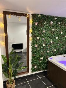a bathroom with a green wall with flowers at Muraille du château avec jacuzzi in Nemours +20 photos