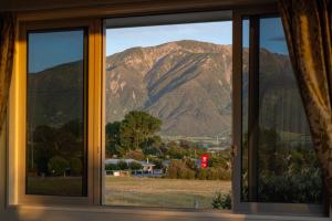 a window with a view of a mountain at Close to Beach, Spacious, Outdoor Living - KK00379 in Kaikoura