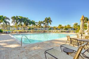 una piscina con mesas, sillas y palmeras en 6 Mi to Beaches Bonita Springs Condo, en Bonita Springs
