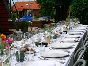 a long table with white plates and glasses on it at Schippershuis in Elahuizen