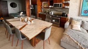 a kitchen with a wooden table and chairs and a couch at Oceanfront Living & Surfing in Cabo Paradisiacal 2BR Condo in San José del Cabo