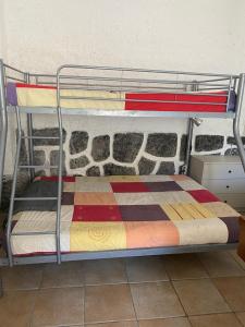 a metal bunk bed with a colorful blanket on it at Refúgio Saloio- LugarTranquilo às Portas de Lisboa in Lousa