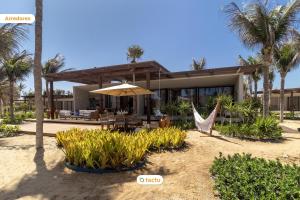 a house on the beach with a hammock and palm trees at Casa Condomínio Origem Fortim Luxo a Beira Mar in Maceio