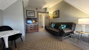 a living room with a leather couch and a tv at Stone Gables Inn in Cleveland