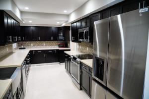 a kitchen with black cabinets and a stainless steel refrigerator at Grand Home Jacuzzi, Heated Pool, Games, BB Court L20 in Miami