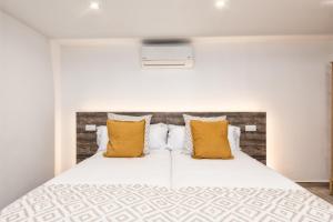 a bedroom with a white bed with yellow pillows at Casa Amanecer I, vistas únicas y paz in Breña Baja