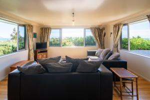 a living room with a black couch and windows at Close to Beach, Spacious, Outdoor Living - KK00379 in Kaikoura +19 photos