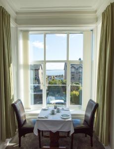 een tafel en twee stoelen voor een groot raam bij Corner Beech House in Grange Over Sands