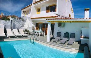a villa with a swimming pool in front of a house at Sunset Chateau -Piscina Aquecida, Vista Mar in Atouguia da Baleia