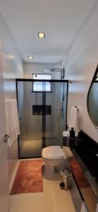 a bathroom with a toilet and a shower with a mirror at APTO NOVO - Praias, Beto Carrero e Aeroporto in Navegantes