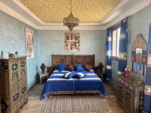 a bedroom with a bed with blue walls and a ceiling at Dar Yamna Maison d'Hôtes in El Gouassem
