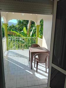 a balcony with a table and chairs on a porch at Haut de Villa LA FLEUR DE CANNE in Lamentin +1 photo