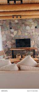 a room with a stone wall with a table and a couch at Entre Cerros in Maimará