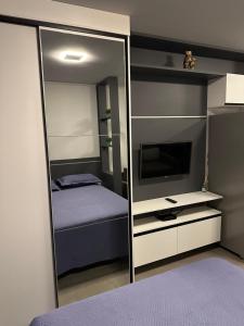 a mirror in a bedroom with a bed and a television at Charmoso Loft em Resort in Xangri-lá +14 photos
