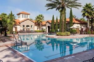 ein Swimmingpool vor einem Haus mit Palmen in der Unterkunft Tuscana Resort Near Disney in Kissimmee