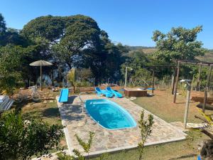 een groot zwembad met blauwe stoelen en een parasol bij Recanto da Represa Carrancas in Carrancas