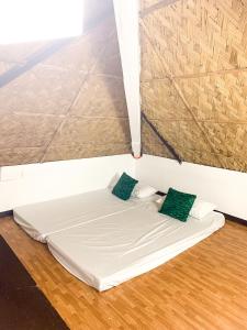 a white bed with two green pillows in a room at Kavanah Suites Tagaytay- Villa 2 in Tagaytay