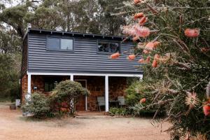 a log cabin with a porch and a tree at Cottage 3 - The Row in Forest Grove