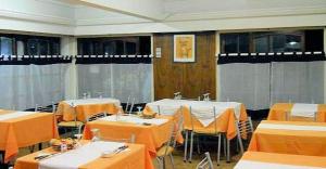a room with tables and chairs with orange table cloth at Hotel Sahara in Villa Gesell