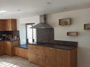 una cucina con armadi in legno e piano di lavoro nero di Grande Maison pour 10 Pers. avec Jardin, Terrasse, BBQ, Près de Bruyères et Gérardmer - FR-1-589-335 a Champ-le-Duc