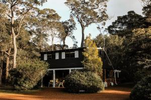 a black house in the woods with trees at Cottage 4 - The Row in Forest Grove