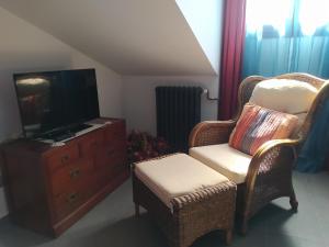 ein Wohnzimmer mit einem TV, einem Stuhl und einer Kommode in der Unterkunft Casa Las Marzas-El Boj in Colombres