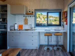 a kitchen with a counter with two stools and a window at Kūkupa Matairangi at Akaroa Lavender in Akaroa