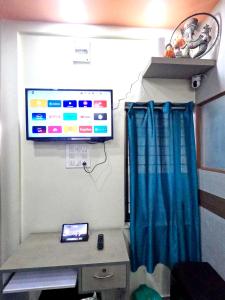 a room with a tv on a wall with a curtain at Utopia Guest house for men in New Town +7 photos
