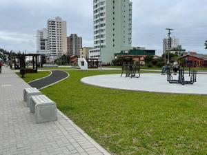 een park met banken in het gras en de gebouwen bij Espaço artemísia in Tramandaí