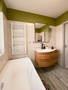 ein Badezimmer mit Badewanne, Waschbecken und Spiegel in der Unterkunft Rhapsody Home - Urban quiet area with Parking&King Bed&Balcony in Târgu Mureș