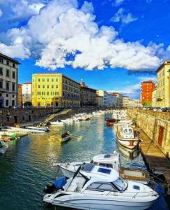 a group of boats docked in a river with buildings at Cozy Stay in City Center in Livorno