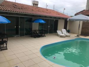 a swimming pool with chairs and umbrellas on a patio at Pousada Souza & Souza in Barra Velha
