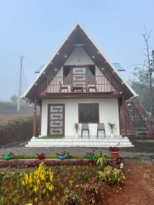 a house with two chairs in front of it at Verdant peaks Homestay in Vagamon