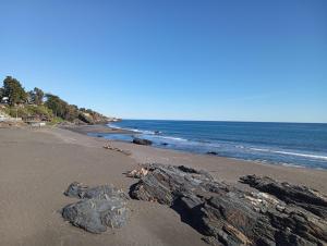 a beach with rocks on the sand and the ocean at Cabaña el descanso in Pelluhue