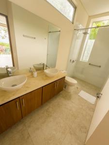 Un baño con dos lavabos, un inodoro y un espejo. en Moderna Casa-Paisajes Increíbles, en Anapoima