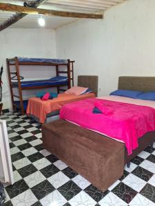 a room with three bunk beds and a checkered floor at Rancho Ohana in Peruíbe