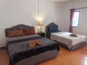 a bedroom with two beds and a table with a lamp at Lanta bluewave Bungkalow in Phra Ae beach