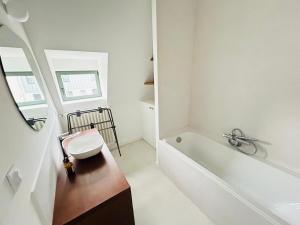 a white bathroom with a tub and a sink at La Maison du Nice Caennais in Caen +30 photos