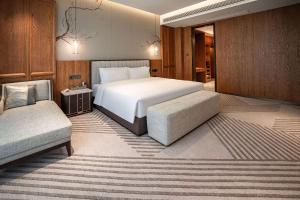 a bedroom with a bed and a chair and a couch at Howard Johnson by Wyndham Jufu Plaza Jinxi in Fuzhou +12 photos