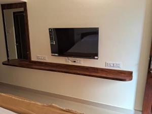 a flat screen tv on a wall in a room at Thavika Gold Mountain Wellness Resort in Tiruvannāmalai
