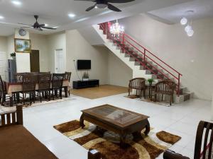 a living room with a staircase and a table and chairs at Ilham Bonda Homestay in Cukai