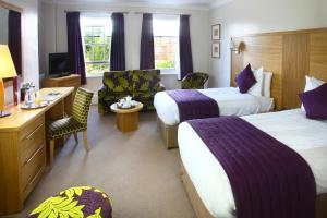 um quarto de hotel com duas camas e uma secretária em The Chequers Hotel em Newbury