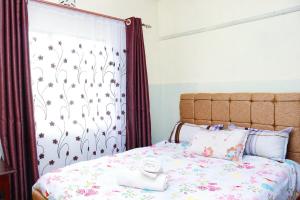 a bedroom with a bed with a floral bedspread at Adorable Homely Stay in Nakuru