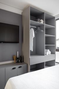 a bedroom with a bed and a tv and shelves at Feel Home - Flat Romântico com Piscina no Rooftop in Cabedelo