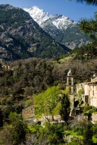 un edificio antiguo con una montaña cubierta de nieve en el fondo en Résidence E CIME ASCO, en Asco