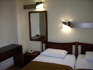 a hotel room with two beds and a mirror at Claridge Hotel in Athens