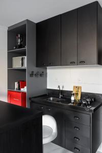 a kitchen with black cabinets and a sink at Feel Home - Flat Romântico com Piscina no Rooftop in Cabedelo +5 photos